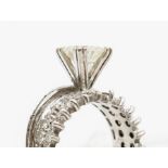 A diamond and white metal ring, the central claw set round brilliant cut diamond weighing approx.