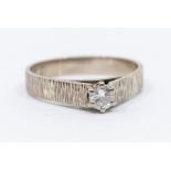 An 18ct white gold diamond solitaire ring, the brilliant cut stone of 0.25ct, rusticated shank, ring
