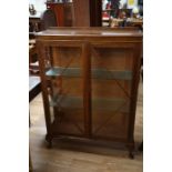 An Art Deco oak display cabinet, fitted with two doors enclosing glass shelves, measuring 128cm