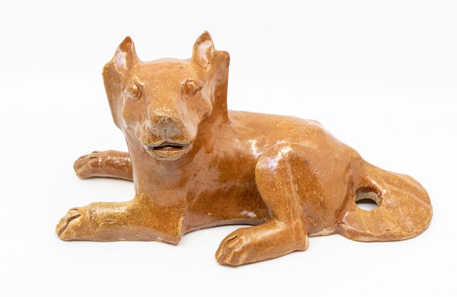 A Chinese brown glazed pottery figure of a dog, the animal reclining, with its head turned to the