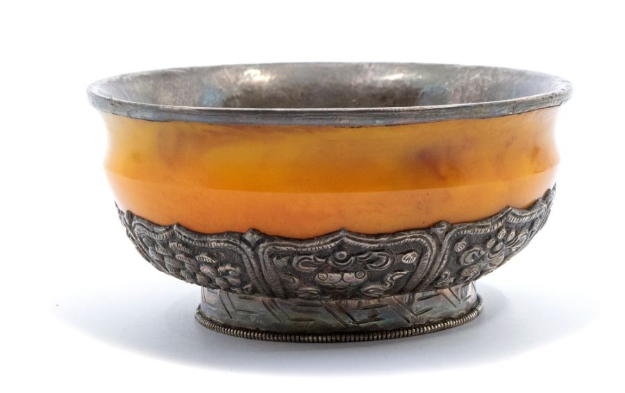 A Bhutan silver-mounted amber bowl, the base of the bowl with lappets decorated in repoussé with the