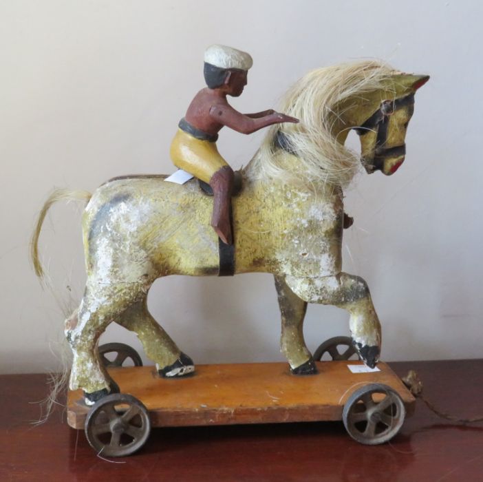 A Victorian painted carved wood pull-along horse, the platform base with metal wheels, and an