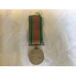 A WWII 1939-1945 Defense Medal with ribbon, the medal with a few nibble to edge and fraying to