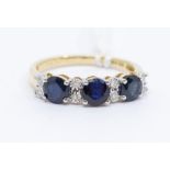 A sapphire and diamond 9ct gold ring, comprising three round cut blue sapphire, claw set in a row,