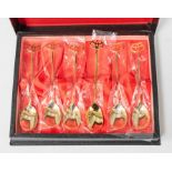 A collection of gold plated tea spoons by Toyota, each with Toyota logo finials, cased