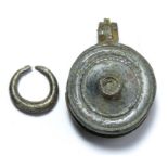 Roman circular bronze seal box containing a small silver penannular ring. The seal box is circular