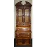 A late 19th century American walnut cylinder bureau bookcase, the broken arch pediment over glazed