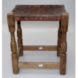 Manner of Robert Thompson (Mouseman), an early 20th century oak stool with woven hide seat on carved