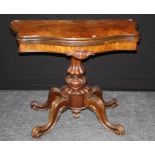 A Victorian figured walnut card table, the serpentine swivel folding top on lobed column, four