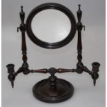 An Edwardian mahogany toilet mirror, the adjustable circular plate over twin candle sconces, on a