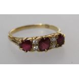 An 18ct ruby and diamond ring, the three oval cut rubies spaced with two pairs of old European cut