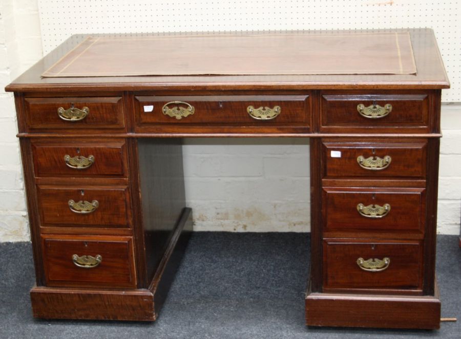 An Edwardian mahogany kneehole pedestal desk having one long and two short frieze drawers, one