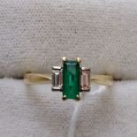 An 18ct emerald and diamond ring, claw set rectangular step cut emerald flanked by two bayonette cut