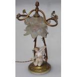 A gilt metal table lamp having a composition female nude under the shade laid on circular base,