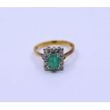 An 18ct emerald and diamond cluster ring, claw set emerald-cut emerald and fourteen eight-cut