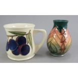 Two twentieth century pieces of Moorcroft tube-lined wares. To include a mug with plums and a floral