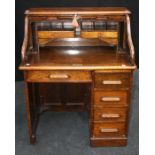 A circa 1920's oak roll top desk, the serpentine tambour enclosing a fitted interior over frieze