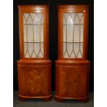 A pair of reproduction yew veneer floor standing corner cabinets, each with glazed door over