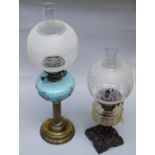 An Edwardian paraffin lamp with blue satin glass reservoir and reeded brass column, together with