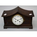 An early 20th century oak mantle clock, the swept barley twist column case enclosing an eight day