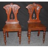 A pair of Victorian mahogany hall chairs, each having anthemion carved rail, tulip carved and