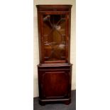 A George III style mahogany standing corner cupboard, the upper stand height over a panel door below