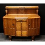 A 1930's oak sideboard, the applied carved upstand over four drawers flanked by cupboard doors, on