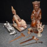 An Indonesian carved hardwood figure, another of a crouching animal, a container,  three krises, a