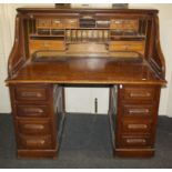 An early 20th century twin pedestal roll top desk, the tambour front enclosing a fitted interior,