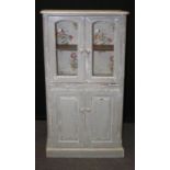 A ' distressed ' painted pine cupboard with a pair of glazed doors over brushing slide and