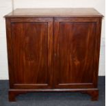 A George III mahogany cupboard, the banded rectangular top, over a pair of panel doors enclosing two