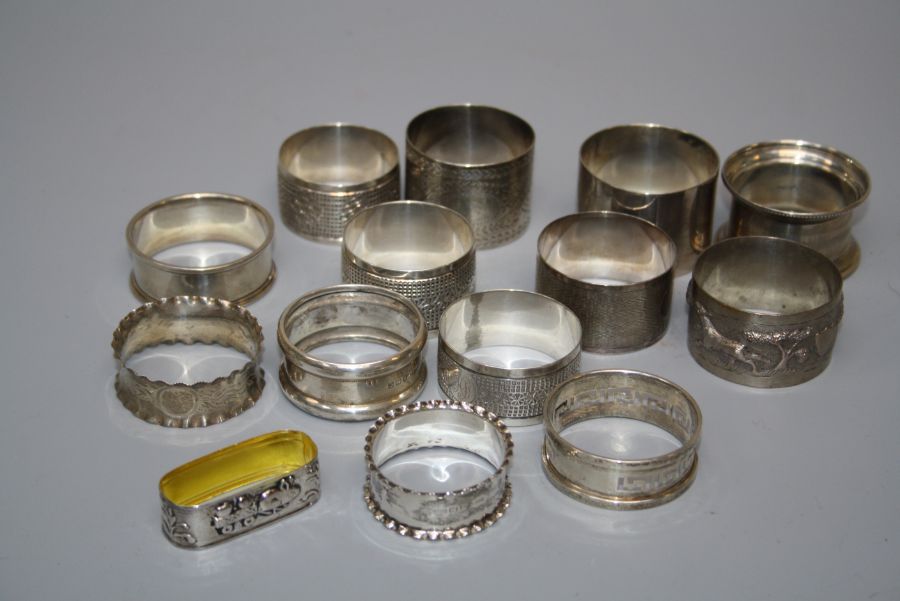 A collection of fourteen hallmarked silver and other white metal serviette rings, various dates