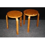 A pair of Alvar Aalto birch occasional tables, the circular tops raised on three thin section