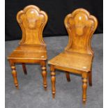 A pair of Victorian oak hall chairs, each with scrolled crown back, shield cartouche, solid seat