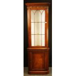 A George III style mahogany standing corner cupboard, the glazed upper height over a panel door