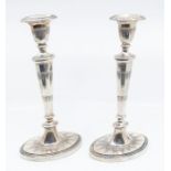 A pair of Continental plated candlesticks, urn shaped sconces above tapering knopped stems on oval