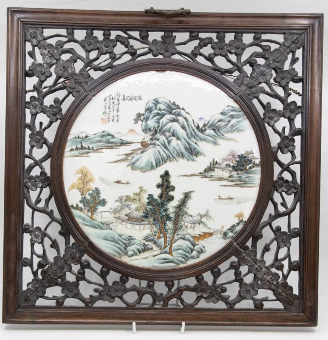 Early 20th Century round Chinese porcelain plaque in carved hard wood frame with flower detail