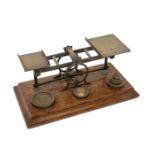 A late 19th Century oak framed brass postal weighing scales with weights, including engraved