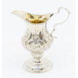 A George III silver ogee shaped cream jug, the body chased with floral decoration, hallmarked
