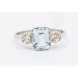 An Art Deco style platinum set aquamarine and diamond ring, comprising a rub over set central