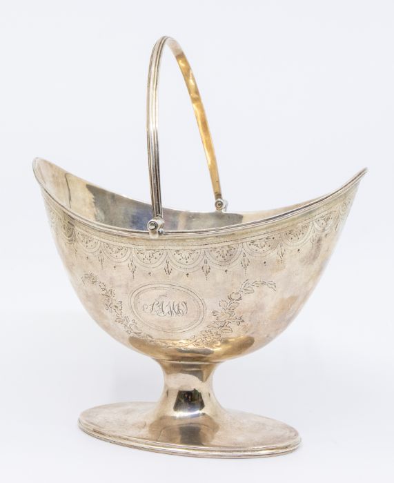 A George III silver boat shaped sugar basket, swing handle, engraved decoration, on oval foot,