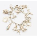 A vintage silver charm bracelet with various charms charms including two shield cartouche, town