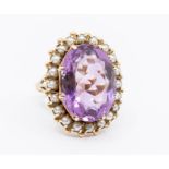 An antique amethyst and pearl set 9ct ring, oval amethyst within a border of half pearls setting