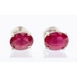 A pair of silver and ruby stud earrings, claw set with oval treated rubies, approx. 7.5mm, post