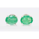 A pair of silver and emerald stud earrings, claw set with oval emeralds,  approx. 7.5mm, post and