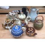 A collection of ceramic teapots, to include:- an example for Bourton on the water with a whicker