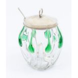 An Arts & Crafts glass condiment jar with silver cover and condiment spoon, the clear and green