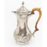 A George III silver pear shaped coffee / hot water jug, domed cover with wyvern finial, chased