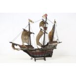 A handmade wooden scale model of a 16th century galleon, detailed rigging, sails and deck areas,