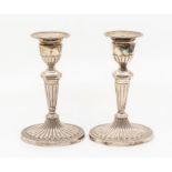 A pair of Neo-Classical style candlesticks, detachable nozzles, tapering stem on paterae feet,